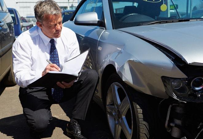 person signing auto insurance document on desk